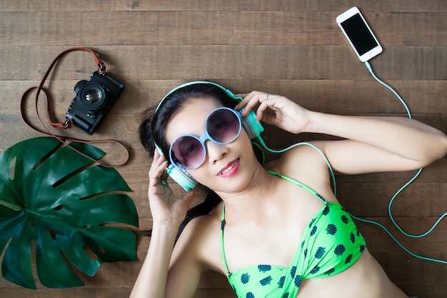 Asian woman in swimwear listening music