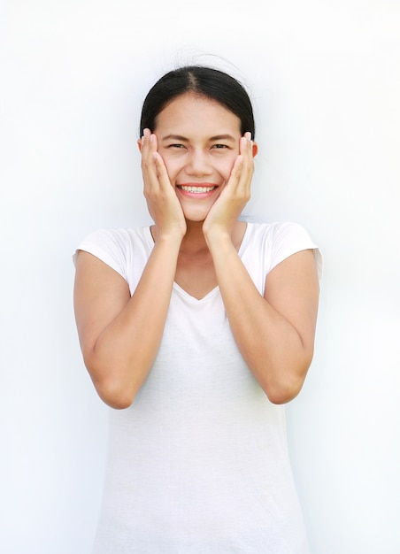 Maglietta asiatica della donna che sta e che tocca la sua guancia con il sorriso su fondo bianco