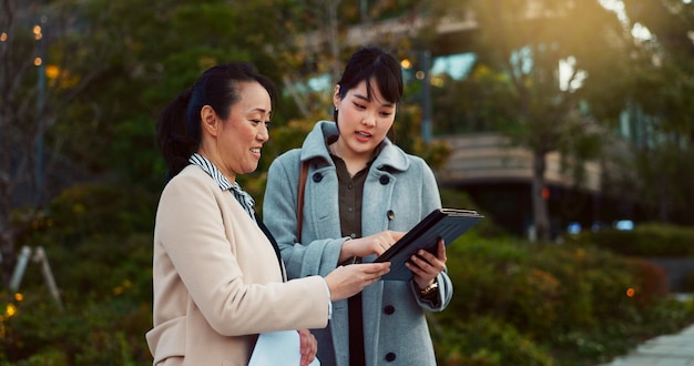 Asian woman tablet and team on sidewalk in city for communication research or social media Business people smile with technology for online search chat or networking on pavement in an urban town