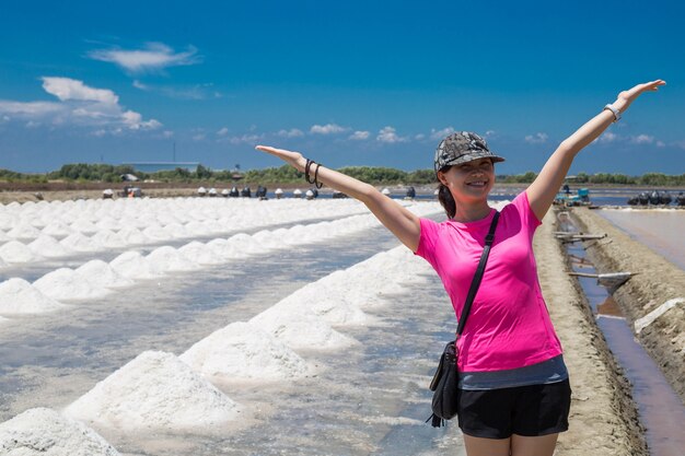 Asian woman take picture front of salt raw material in thailand with blue sky