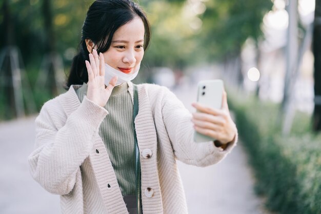 Asian woman takes off her face mask to use her phone