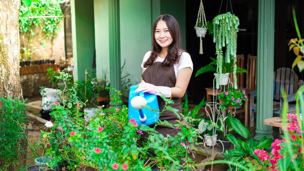 Asian woman taking care watering flower at home garden