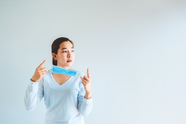 Asian woman taking off her protection mask