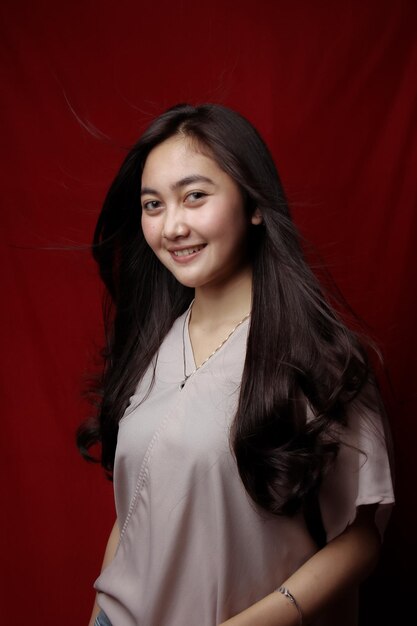 Asian woman taking photo on a red background happy asian woman\
beautiful asian woman with long and straight hair