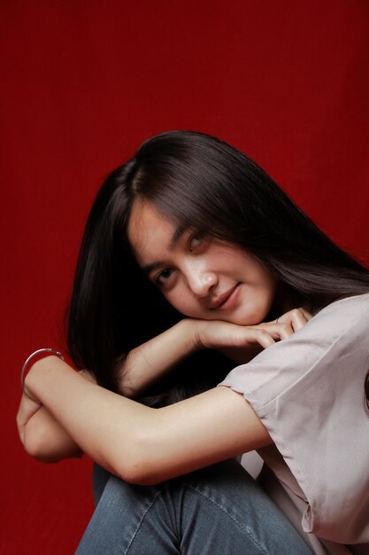 Asian woman taking photo on a red background happy asian woman\
beautiful asian woman with long and straight hair