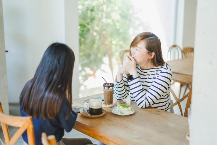 Photo アジアの女性がコーヒーショップで幸せな気持ちで友人と話します