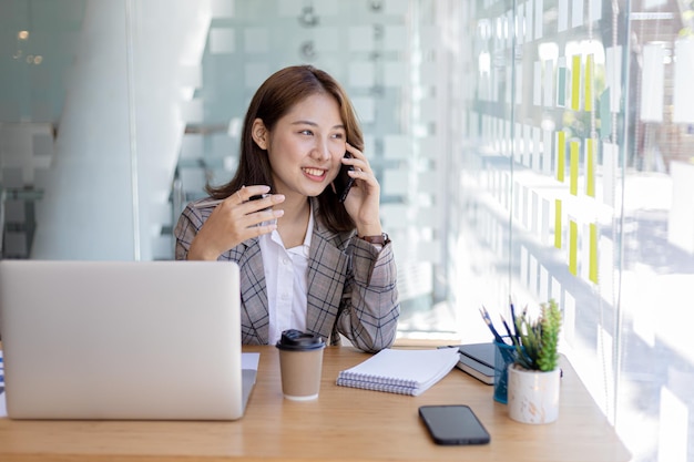 Asian woman talking on the phone, she is a salesperson in a startup company, she is calling customers to sell products and promotions. Concept of selling products through telephone channels.