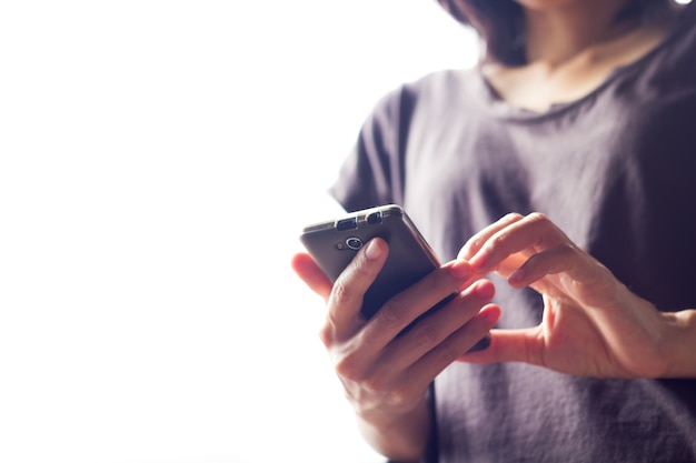 Asian woman touching smartphone bright background, closeup.