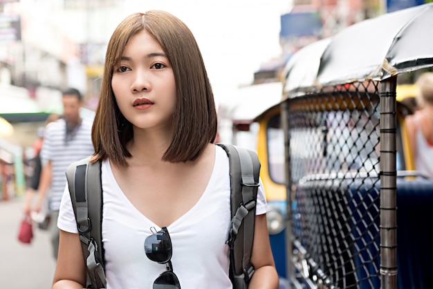 Viaggiatore con zaino e sacco a pelo turistico della donna asiatica che cammina in strada di khao san, bangkok - tailandia