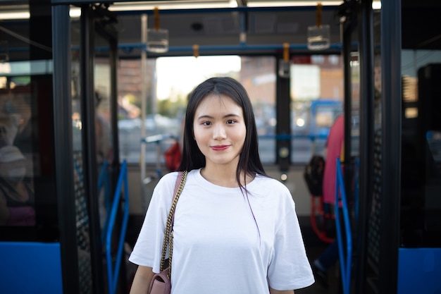 Asian woman tourist get out through doors after ride in public\
transport stop bus or tram