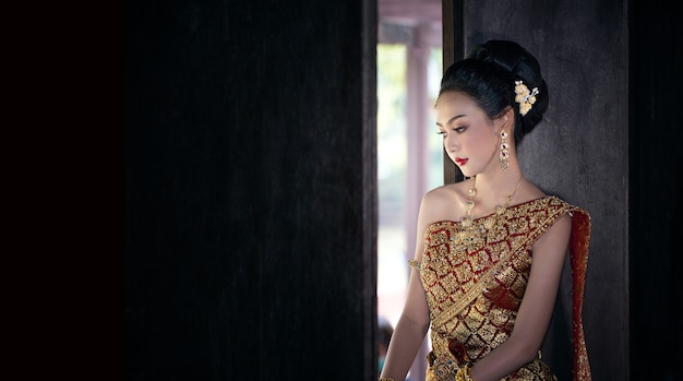 Asian woman in traditional Thai costume standing by the window