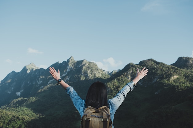 Asian woman traveler arms up in the air at view of mountain