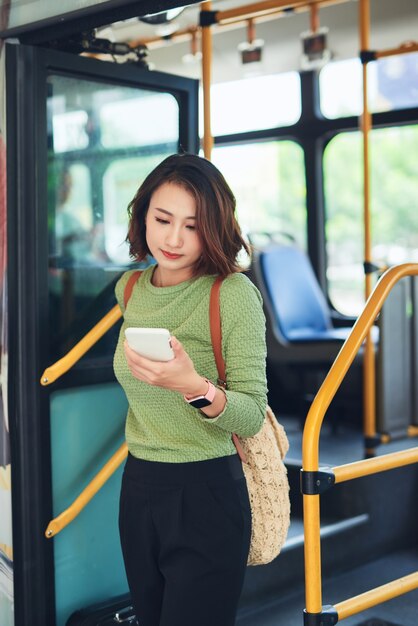 ターミナルでバスを降りるアジアの女性旅行者