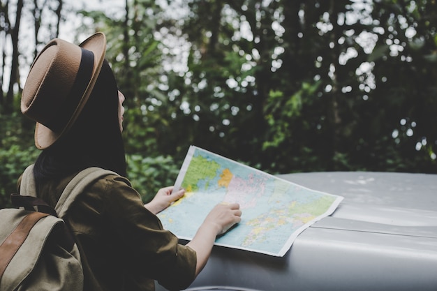 写真 アジアの女性旅行者は、フォレスト内の道順を見つけるために地図を持っています。