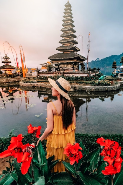 Donna asiatica che viaggia a pura ulun danu beratan il tempio galleggiante di bali, indonesia in mattinata.