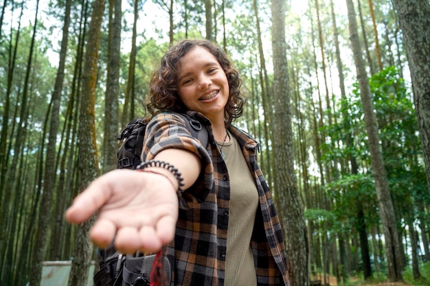 Asian woman trekking in the forest with an open hand