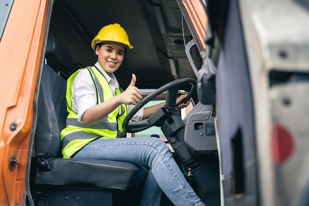 カメラを見ているトラックのキャビンに座っているアジアの女性トラック運転手