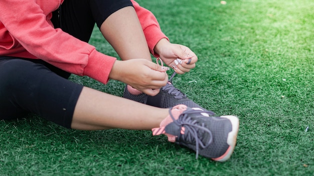 Foto donna asiatica che lega le scarpe da ginnastica prima di correre. chiudere le gambe