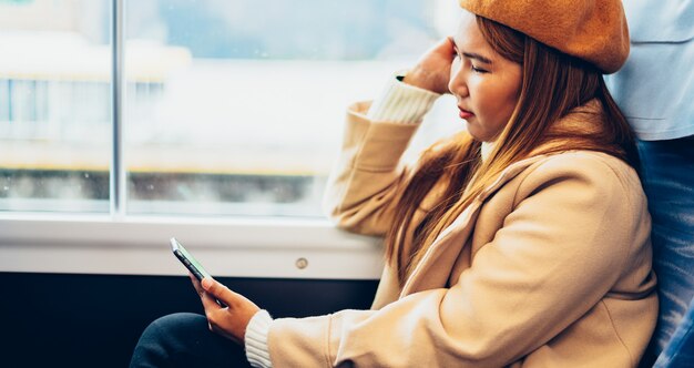 Smartphone asiatico di uso della donna sul treno e viaggio nel giappone