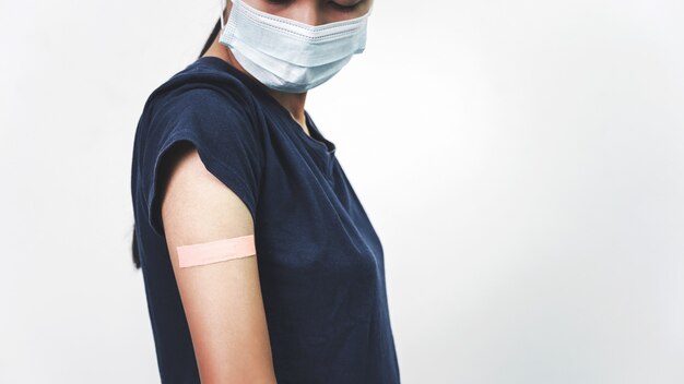 Asian woman using adhesive bandage plaster on her arm after injection vaccine.