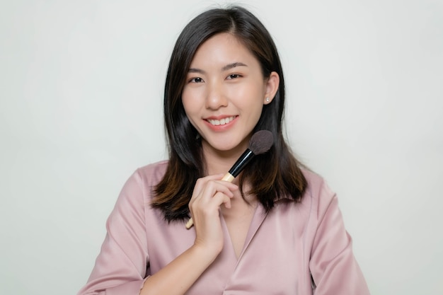 An Asian woman using a blush brush