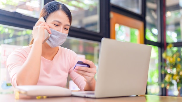 Asian woman using credit card for online shopping and home delivery. New normal life after COVID-19. Stay home and Social Distancing.