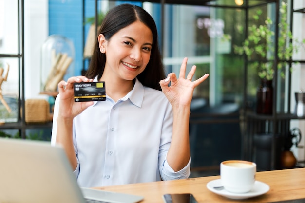 커피 숍 카페에서 온라인 쇼핑 신용 카드를 사용하는 아시아 여성