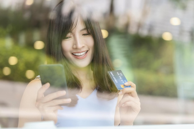 온라인 쇼핑을 위해 휴대전화로 신용카드를 사용하는 아시아 여성
