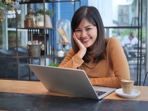 Donna asiatica che utilizza computer portatile nel caffè della caffetteria