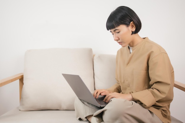 Asian woman using laptop while sitting on the sofa at home