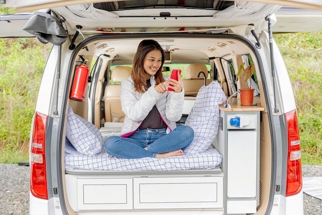 Asian woman using mobile phone inside the campervan