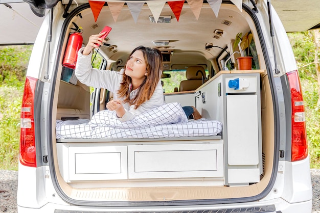 Asian woman using mobile phone inside the campervan