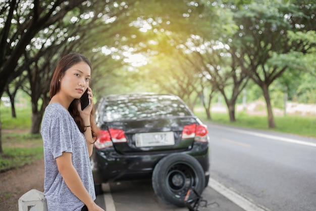 Asian woman using mobile phone while looking and Stressed woman after  broken down car on street