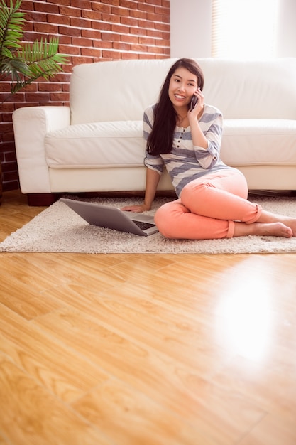 Asian woman using phone on floor