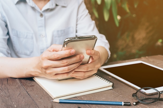 Asian woman using phone in garden at coffee shop with vintage tone.