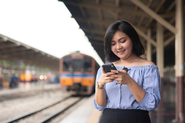 Asian woman using phone at train station