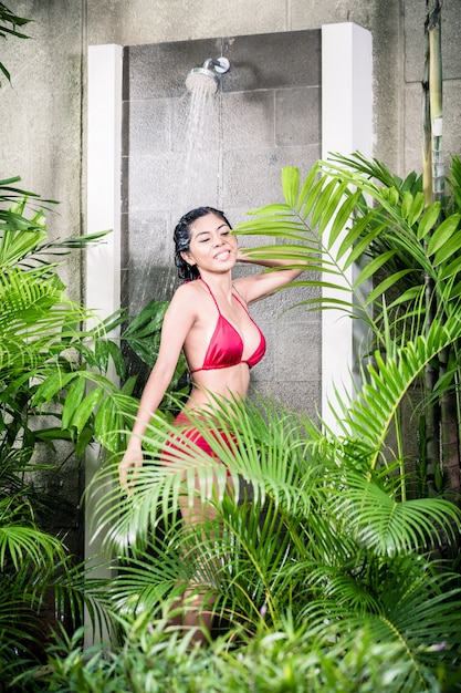 Asian woman using shower in tropical garden