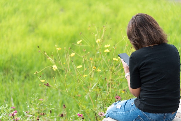 Asian woman using smartphone while relax at the garden