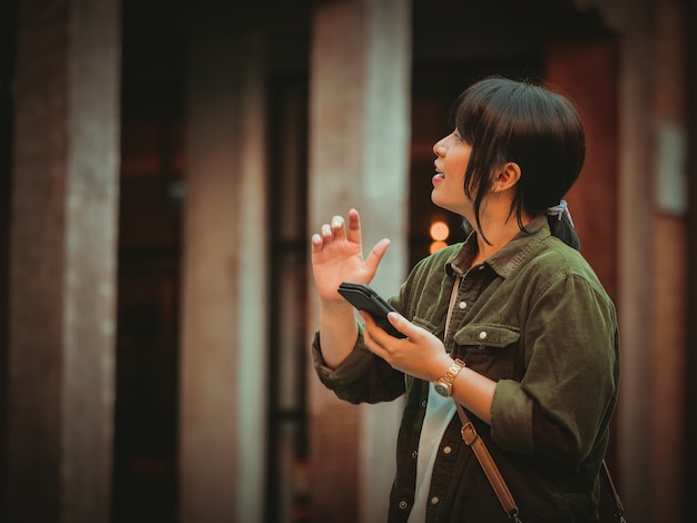 Asian woman using smartphone with happy mood in shopping mall