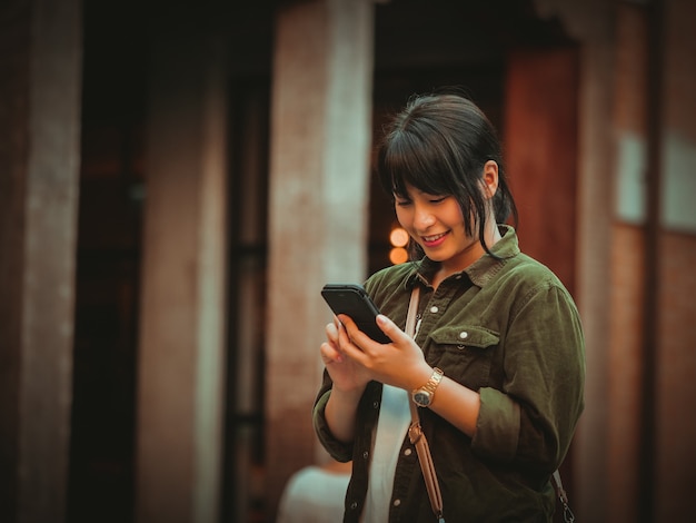 Asian woman using smartphone with happy mood in shopping mall