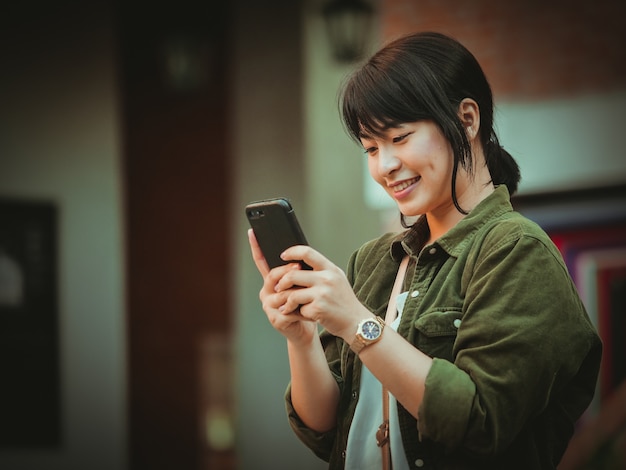 Asian woman using smartphone with happy mood in shopping mall