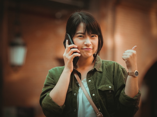 Asian woman using smartphone with happy mood in shopping mall