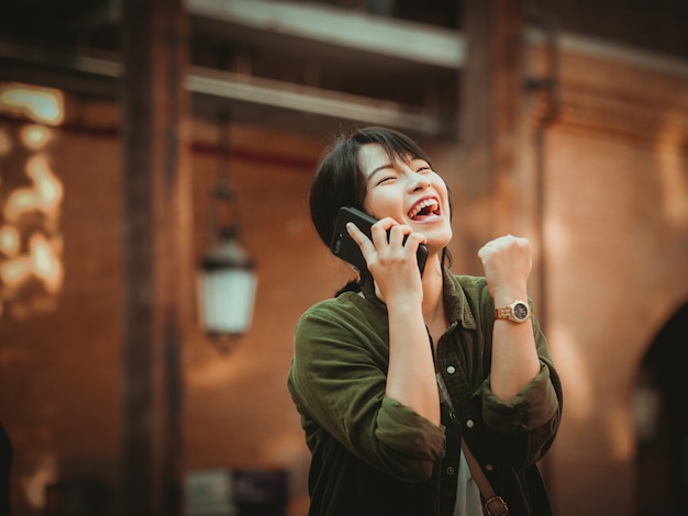 Asian woman using smartphone with happy mood in shopping mall