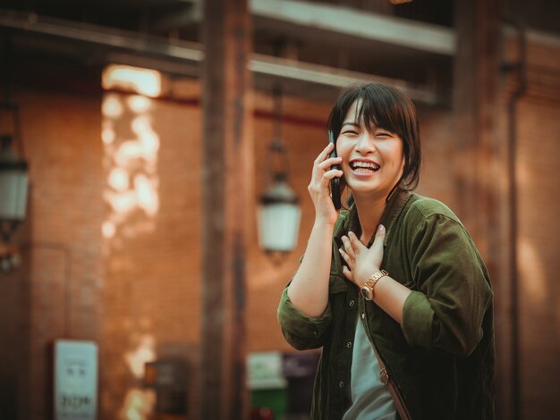 Asian woman using smartphone with happy mood in shopping mall