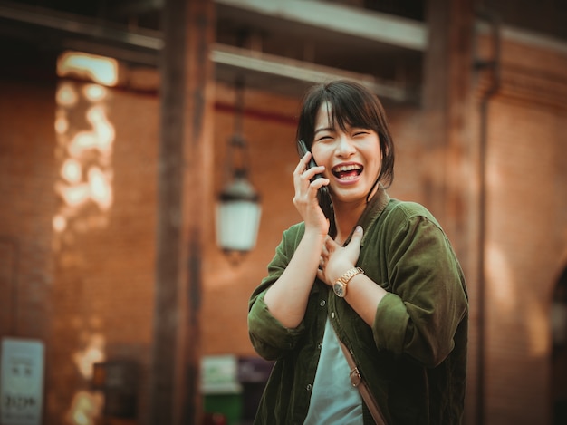 Asian woman using smartphone with happy mood in shopping mall