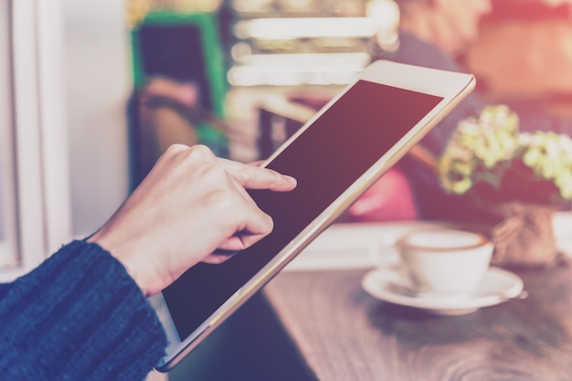 Asian woman using tablet computer in coffee shop with Vintage tone.