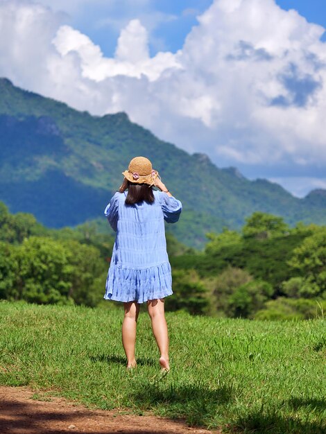 山の景色を望む自然な緑のガラスのフィールドでアジアの女性の休暇