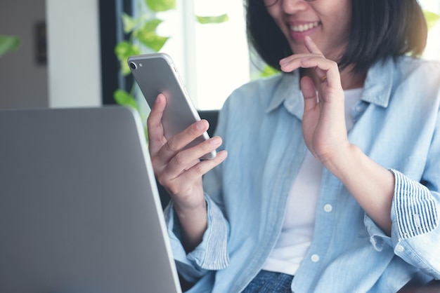 Foto videochiamate di una donna asiatica tramite l'app per riunioni online del telefono cellulare che lavora presso la caffetteria