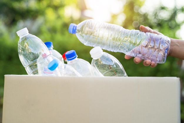 Азиатская женщина-волонтер носит пластиковые бутылки с водой в мусорный ящик мусор в парке перерабатывает отходы концепция экологии окружающей среды