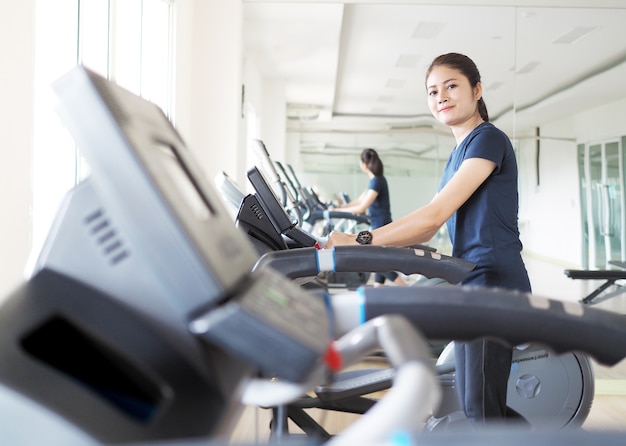 Asian woman walking,  running on treadmill gym workout.